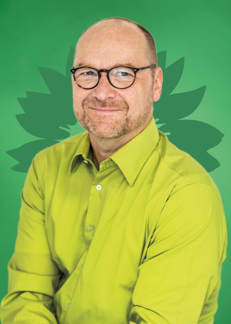Portrait von Sascha Wycisk vor einer stilisierten grünen Sonnenblume