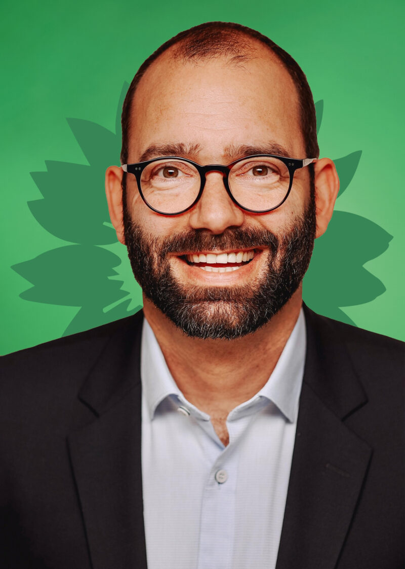 Portrait von Michael Verspohl vor einer stilisierten grünen Sonnenblume